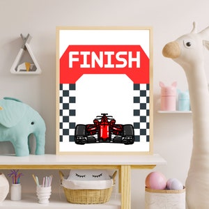 Peut inclure: Une affiche imprimable repr&eacute;sentant une voiture de course rouge franchissant une ligne d'arriv&eacute;e &agrave; damier avec le mot "FINISH" sur une banni&egrave;re rouge au-dessus.