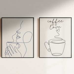 May include: Two framed black and white line art prints. The left print features a woman drinking from a cup with steam rising from the cup. The right print features a cup of coffee with steam rising from the cup and the text "coffee love" with a heart.