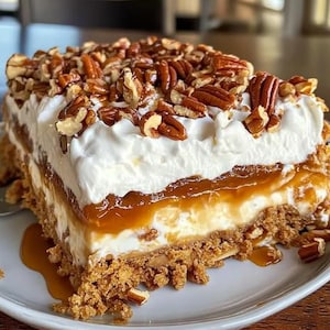 May include: A layered dessert with a graham cracker crust, a layer of caramel, a layer of whipped cream, and a layer of pecans.