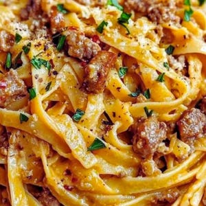 May include: A close-up of a plate of pasta with a creamy sauce and ground meat. The pasta is cooked al dente and the sauce is rich and flavorful. The dish is garnished with fresh parsley.
