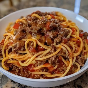 Puede incluir: Un cuenco blanco lleno de espaguetis y una rica salsa de carne. La pasta es dorada y la salsa es de un rojo vibrante con trozos visibles de carne y tomate. Una comida abundante y deliciosa.