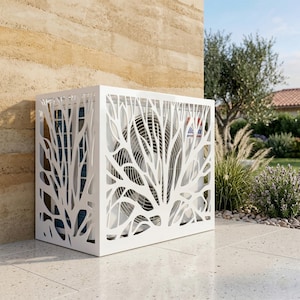May include: A white, decorative air conditioning unit cover with a tree branch design. The cover is rectangular and sits on a patio. The background includes a beige wall, greenery, and a blue sky.
