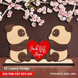 Könnte beinhalten: Ein Holz-Panda-Bärenpaar hält ein rotes Herz mit der Aufschrift "Jack Love Shopu". Das Design ist zweilagig mit einer Dicke von 3 mm oder 4 mm. Der Sockel ist rechteckig, mit Kirschblüten im Hintergrund.