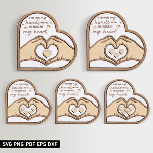 Puede incluir: Cinco letreros de madera en forma de corazón con el texto "Si crees que mis manos están llenas, deberías ver mi corazón." Los letreros presentan un par de manos formando un corazón con corazones más pequeños dentro.