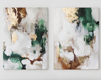 May include: Two abstract paintings with gold leaf accents. The artwork features a mix of colors, including white, green, brown, and gold. The paintings are displayed above a gray sofa with beige pillows, creating a modern and elegant aesthetic.