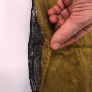 Puede incluir: Primer plano del interior de una prenda, mostrando el forro. El forro es una tela estampada de color azul oscuro y negro. La tela exterior es de color amarillo mostaza.