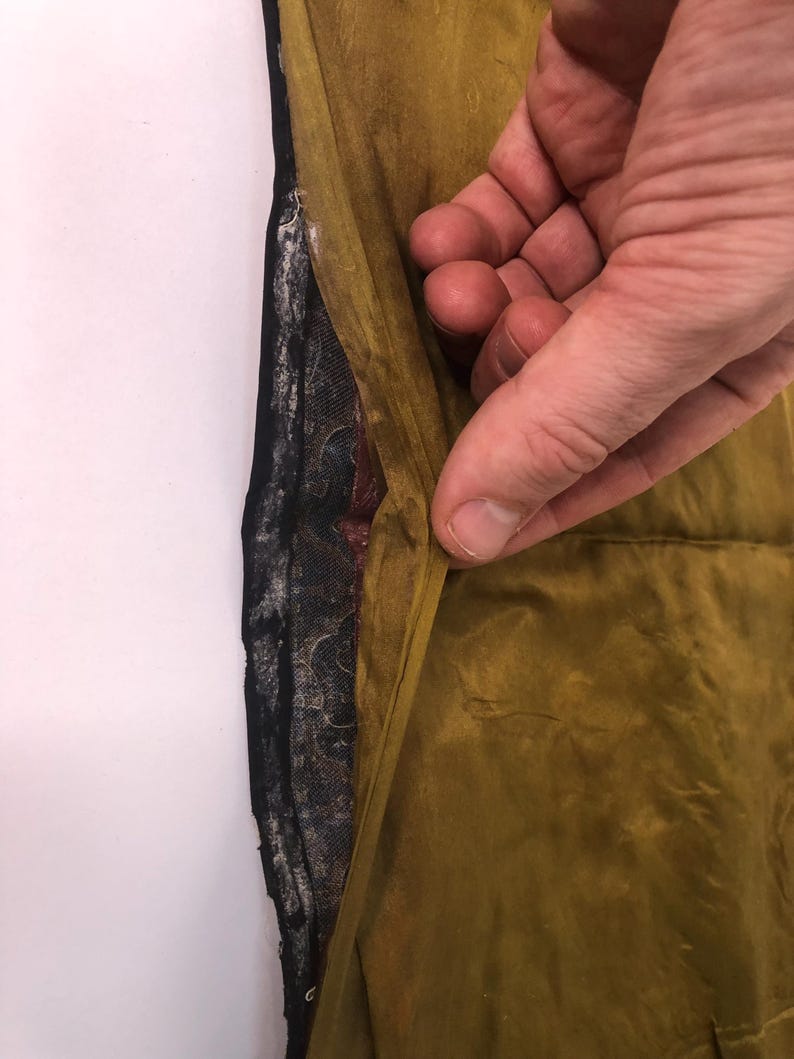 Puede incluir: Primer plano del interior de una prenda, mostrando el forro. El forro es una tela estampada de color azul oscuro y negro. La tela exterior es de color amarillo mostaza.