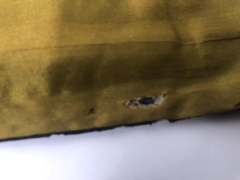 Puede incluir: Primer plano de una tela de color amarillo mostaza con un peque&ntilde;o agujero en el centro.