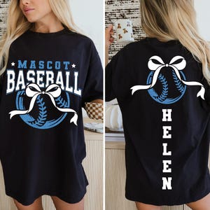 Peut inclure: T-shirt noir avec un motif sur le th&egrave;me du baseball. Le devant affiche "MASCOT BASEBALL" en blanc et bleu, avec un graphisme de baseball et de n&oelig;ud. Le dos pr&eacute;sente un graphisme de baseball avec un n&oelig;ud et le nom "HELEN" en blanc.