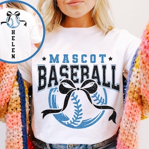 Peut inclure: T-shirt blanc avec l'inscription "MASCOT BASEBALL" en noir et bleu, un graphisme de baseball et un n&oelig;ud noir. Le dos du t-shirt pr&eacute;sente un graphisme de baseball avec un n&oelig;ud et le nom "HELEN" en lettres noires verticales.