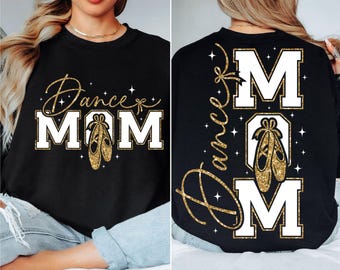 May include: Black sweatshirt with the words "Dance Mom" in gold glitter script and block letters. The design includes a pair of gold ballet shoes. The back of the sweatshirt also features the words "Dance Mom" and ballet shoes.