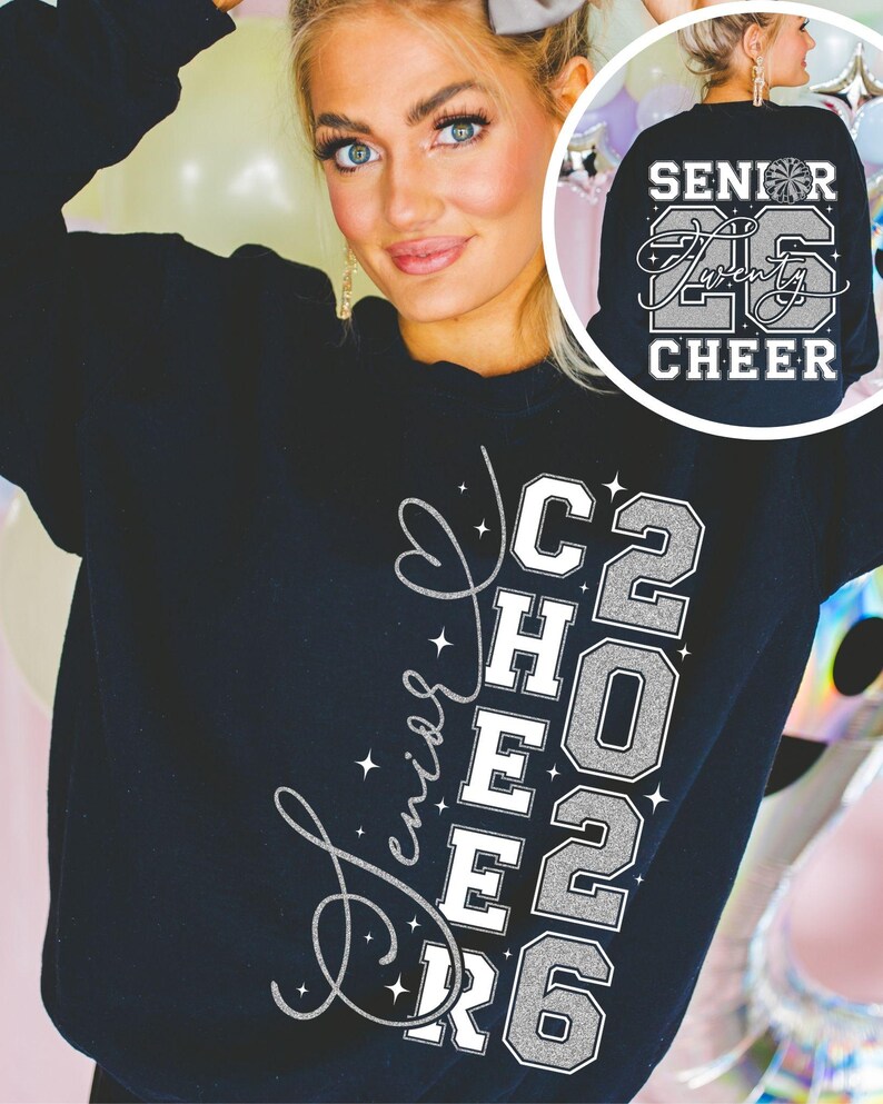 May include: Black sweatshirt with the words "Senior Cheer 2026" in white and silver glitter lettering. The back of the sweatshirt has the words "Senior Twenty 26 Cheer" with a cheerleader graphic. The sweatshirt is worn by a person.