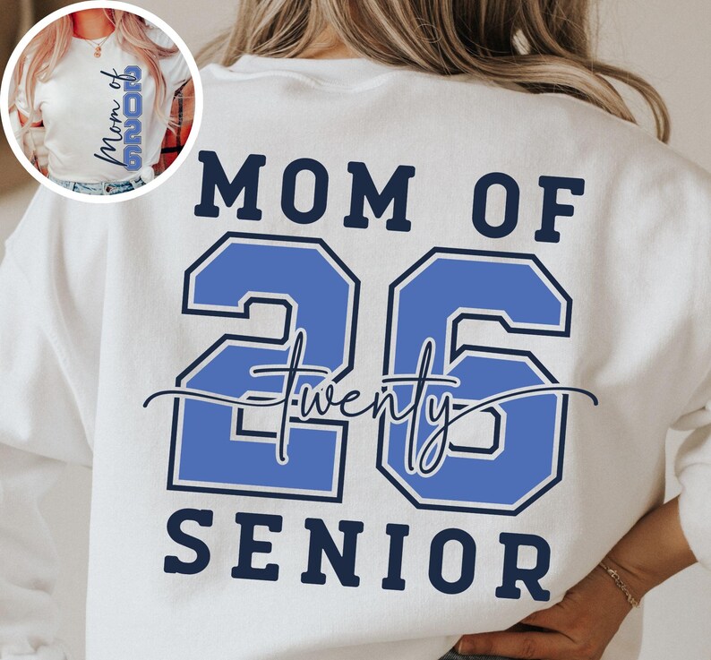 May include: White sweatshirt with the text "MOM OF 26 SENIOR" in navy blue and light blue. The number "26" is in a bold, outlined font. The word "twenty" is written in cursive between the numbers.