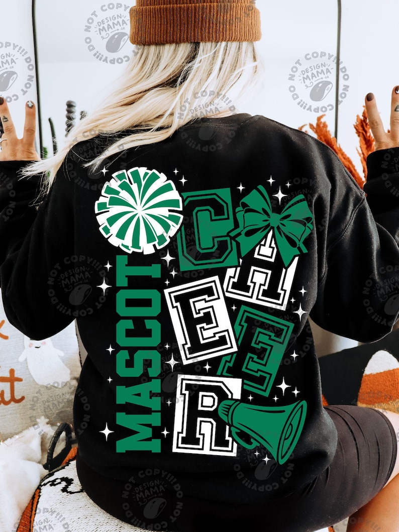 May include: Black sweatshirt with a green and white cheerleader design. The design includes a pom-pom, bow, megaphone, and the word "MASCOT" vertically. The word "CHEER" is also displayed in a block letter style.