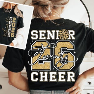 May include: Black t-shirt with gold glitter text and a cheerleader pom-pom graphic. The back of the shirt reads "SENIOR Twenty 26 CHEER". The front of the shirt has "CHEER 2026" in gold glitter. A perfect gift for cheerleaders.