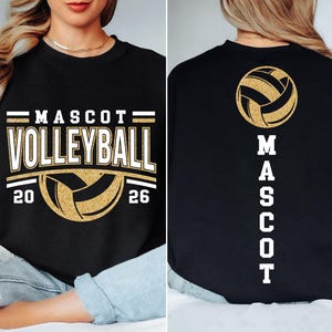 Op de afbeelding: Zwart sweatshirt met gouden en witte tekst en afbeeldingen. De voorkant toont "MASCOT VOLLEYBALL" met een volleybalafbeelding en de cijfers "20" en "26". De achterkant heeft een volleybalafbeelding en het woord "MASCOT" verticaal.