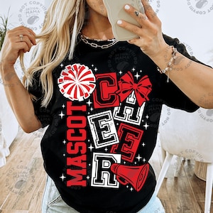 May include: Black t-shirt with a cheerleading design. The design includes the word "MASCOT" in red, and the word "CHEER" in red and white block letters. A red and white pom-pom, bow, and megaphone are also featured.