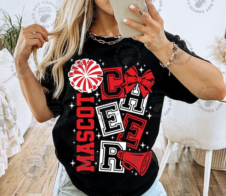 May include: Black t-shirt with a cheerleading design. The design includes the word "MASCOT" in red, and the word "CHEER" in red and white block letters. A red and white pom-pom, bow, and megaphone are also featured.