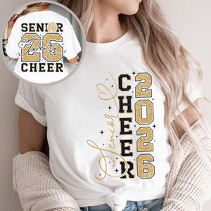 May include: White t-shirt with the text "Senior Twenty Cheer 2026" in black and gold glitter lettering. The design includes a cheerleader pom-pom graphic. The shirt is a casual style.
