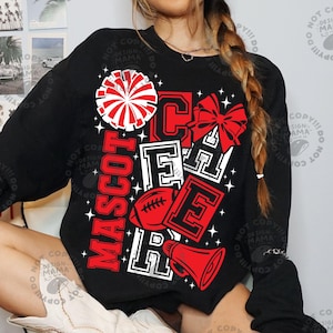 May include: A black long-sleeve sweatshirt featuring a graphic print with the word CHEER in large red and white block letters. The design includes a red and white pom-pom, a red bow, a red football, a red megaphone, and small white star accents.