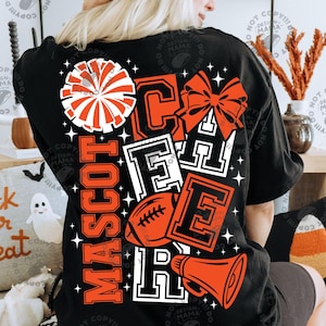 May include: A black t-shirt featuring a large graphic on the back with the word CHEER in bold block letters, a pom-pom, a hair bow, a football, and a megaphone. The design includes the word MASCOT in orange and white, accented by stars.