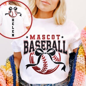 Peut inclure: T-shirt blanc avec un motif sur le th&egrave;me du baseball. Le devant affiche "MASCOT BASEBALL" en rouge et noir, avec un graphisme de baseball et de n&oelig;ud. Le dos du t-shirt pr&eacute;sente un graphisme de baseball et le nom "HELEN" en noir.
