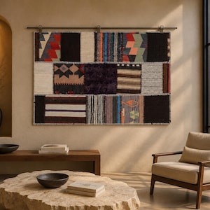 May include: A rectangular wall hanging tapestry featuring a patchwork design of various woven fabric segments in black, white, red, blue, and tan colors, suspended from a dark metal rod with clips against a neutral-toned wall surface.