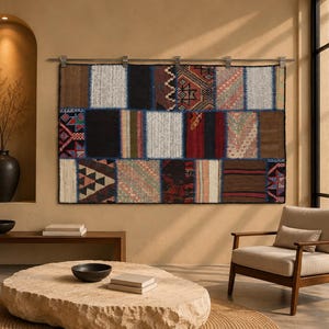 Può includere: Un arazzo rettangolare da parete caratterizzato da un design patchwork di vari pannelli in tessuto intrecciato nei toni del nero, marrone, rosso, bianco e blu, con diversi motivi geometrici e texture solide, appeso a un'asta metallica con clip.
