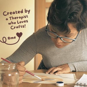 Pu&ograve; includere: Una persona con gli occhiali dipinge con acquerelli. L'immagine include un barattolo di vetro, un piccolo contenitore di vernice blu e un taccuino. Il testo sul muro recita "Created by a Therapist who Loves Crafts!" con un cuore e l'hashtag "#me".