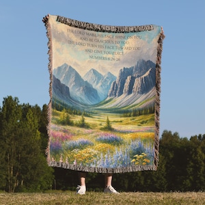 Peut inclure: Une couverture en tissu tissé avec un paysage de montagne et un verset biblique de Nombres 6:24-26. Le verset dit : "Que l'Éternel fasse briller sa face sur toi, et qu'il te soit favorable ; que l'Éternel tourne sa face vers toi, et qu'il te donne la paix."