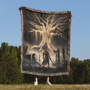May include: A woven tapestry throw blanket featuring a dark silhouette of a knight standing in front of a large, golden tree with roots that spread across the ground. The background is a dark, misty forest with tall, stone pillars.
