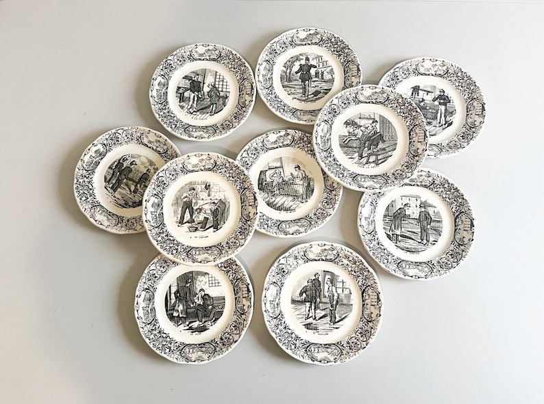 K&ouml;nnte beinhalten: Set aus zehn wei&szlig;en Keramiktellern mit Schwarzwei&szlig;illustrationen. Jeder Teller zeigt eine andere Szene mit Personen in verschiedenen Umgebungen.
