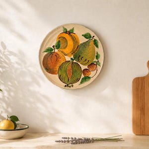 Puede incluir: Plato de cerámica redondo pintado a mano con ilustraciones de frutas coloridas. El plato presenta un diseño vibrante con naranjas, peras y otras frutas, agregando un toque de encanto rústico a cualquier cocina o comedor.