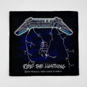 Op de afbeelding: Zwart-witte geborduurde patch met de bandnaam "Metallica" en de albumtitel "Ride the Lightning" in witte tekst. De patch heeft een bliksemontwerp en een microfoon.