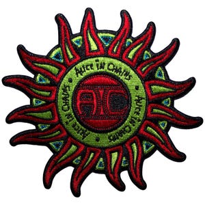 Könnte beinhalten: Gestickter Aufnäher mit einem stilisierten Sonnendesign in Rot, Grün und Schwarz. Der Mittelkreis zeigt die Buchstaben "AIC" in Rot, umgeben vom Text "Alice in Chains" in Grün.