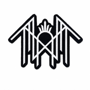 Könnte beinhalten: Ein schwarz-weiß bestickter Aufnäher mit einem symmetrischen geometrischen Design. Das Emblem besteht aus scharfen, kantigen Linien, die einen zentralen Bogen mit einem Sonnenstrahlenmotiv bilden, flankiert von zwei flügelartigen Strukturen mit vertikalen Balken.