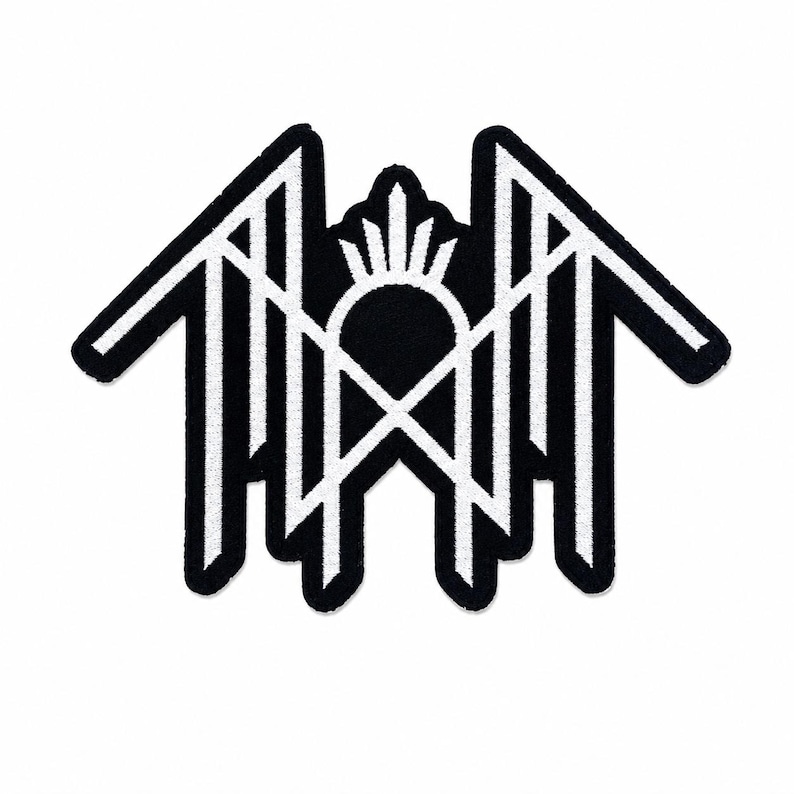 May include: A black and white embroidered patch featuring a symmetrical geometric design. The emblem consists of sharp, angular lines forming a central arch topped with a sunburst motif, flanked by two wing-like structures with vertical bars.