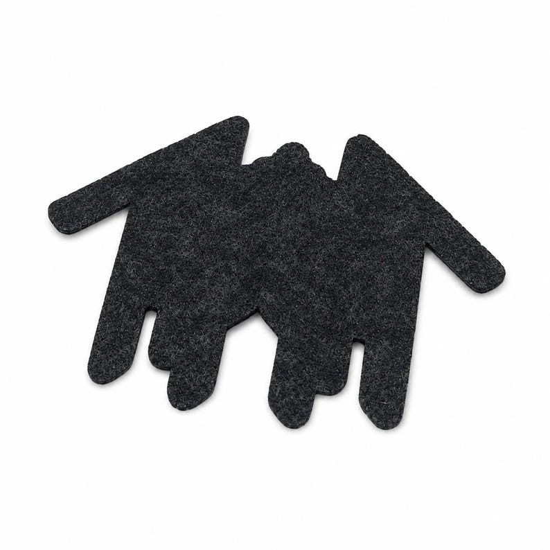 May include: A dark charcoal gray felt coaster shaped like a stylized bat with outstretched wings and pointed ears. The surface has a textured, fibrous appearance characteristic of pressed felt material, featuring a flat, die-cut silhouette design.