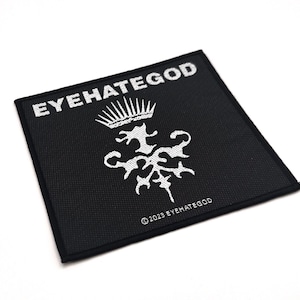 May include: A square black patch featuring white text and a white emblem. The text "EYEHATEGOD" is at the top, with a crown above a stylized design. The text "&copy; 2023 EYEHATEGOD" is at the bottom.