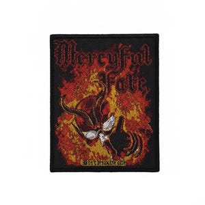 Könnte beinhalten: Ein rechteckiger bestickter Aufnäher mit schwarzem Rand, der den Text Mercyful Fate in gotischer Schrift über einer Grafik eines gehörnten Schädels zeigt, umgeben von orangefarbenen und gelben Flammen, mit dem Text Don't Break the Oath unten.