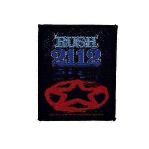 May include: A rectangular black embroidered patch featuring the text RUSH 2112 in light blue with a white outline. Below the text is a red star emblem with a black center. The bottom edge includes the text 2015 ANTHEM ENTERTAINMENT in small font.