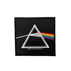 Op de afbeelding: Een vierkante zwarte geborduurde patch met een wit omlijnd prisma-ontwerp, waarbij een lichtstraal van links binnenkomt en een regenbogenspectrum naar rechts uitstraalt. De tekst onderaan luidt © 2023 PINK FLOYD (1987) LTD.