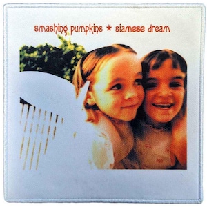 Könnte beinhalten: Quadratischer Aufnäher mit dem Albumcover von Smashing Pumpkins' "Siamese Dream". Das Bild zeigt zwei junge Mädchen, die lächeln, mit dem Bandnamen und Albumtitel in roter Schrift. Der Aufnäher hat einen weißen Rand.