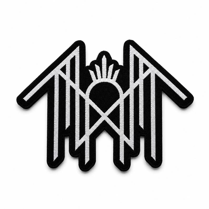 May include: A black and white embroidered patch featuring a symmetrical geometric design. The emblem consists of sharp, angular lines forming a house-like structure with a central arched element topped by a small, radiating sunburst motif.