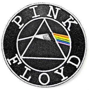 Könnte beinhalten: Ein runder, bestickter Aufnäher mit schwarzem Hintergrund und weißem Rand. Das Design zeigt ein weißes dreieckiges Prisma, in das links ein weißer Lichtstrahl eintritt und rechts als Regenbogenspektrum austritt. Der Text PINK FLOYD ist in weißen Großbuchstaben entlang des Randes gestickt.