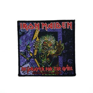 Può includere: Una toppa ricamata quadrata con il logo Iron Maiden in rosso nella parte superiore e la scritta No Prayer for the Dying in rosso nella parte inferiore. Il grafico centrale raffigura una creatura verde con capelli a punta.