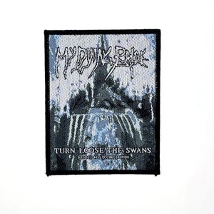 Könnte beinhalten: Ein rechteckiger Webaufnäher mit einer blau-schwarzen Grafik einer dunklen, gotischen Struktur. Der Text MY DYING BRIDE steht oben, während TURN LOOSE THE SWANS und 2023 MY DYING BRIDE in Weiß am unteren Rand des Designs gedruckt sind.