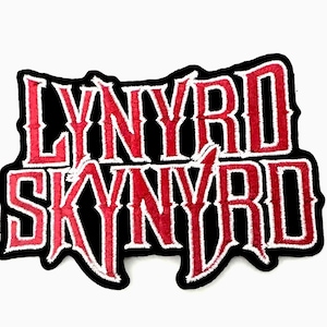 Pode incluir: Um emblema bordado com o texto "LYNYRD SKYNYRD" em letras vermelhas em negrito com estilo serifado e uma borda branca espessa. As letras estão sobre um fundo preto sólido, criando um design de alto contraste com uma borda serrilhada distinta.