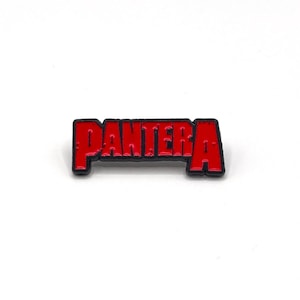 May include: A red and black enamel pin with the word "PANTERA" in a bold, blocky font. The pin has a black outline and a glossy finish. This music-themed accessory is suitable for jackets or bags.