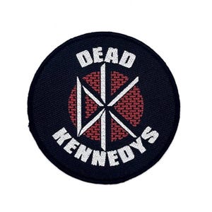 Könnte beinhalten: Ein kreisförmiger gestickter Aufnäher mit schwarzem Hintergrund und weißem Rand. Das Design zeigt den weißen Schriftzug DEAD KENNEDYS, der um ein zentrales weißes Logo mit einem stilisierten DK-Symbol auf rotem kreisförmigem Grund angeordnet ist.